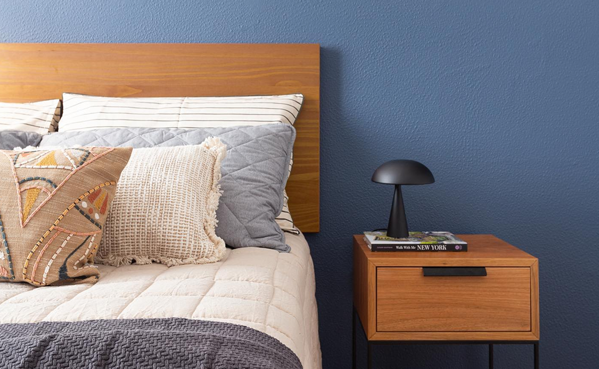 quarto com parede azul marinho atrás da cama.