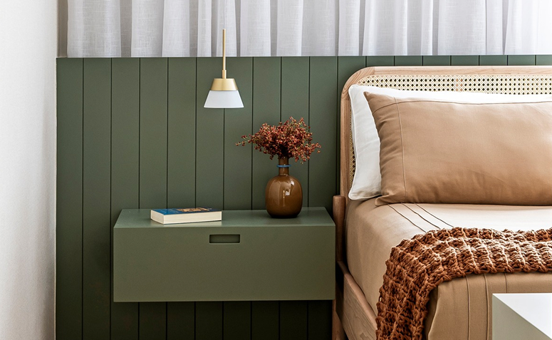 Quarto com mesa de cabeceira com um vaso de flores e um livro