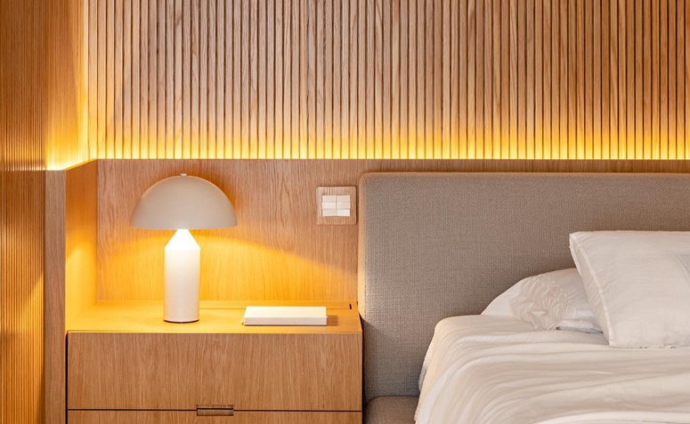 Quarto com iluminação indireta sobre a cama e luminária representando iluminação suave