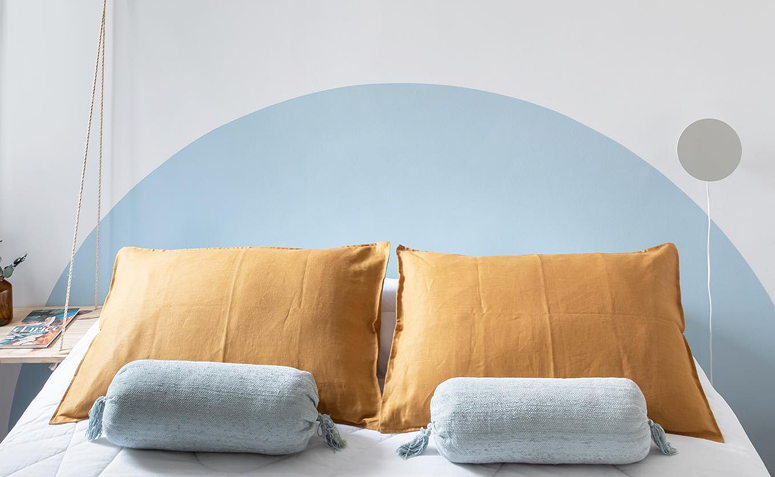 parede branca com círculo azul pintado atrás de uma cama