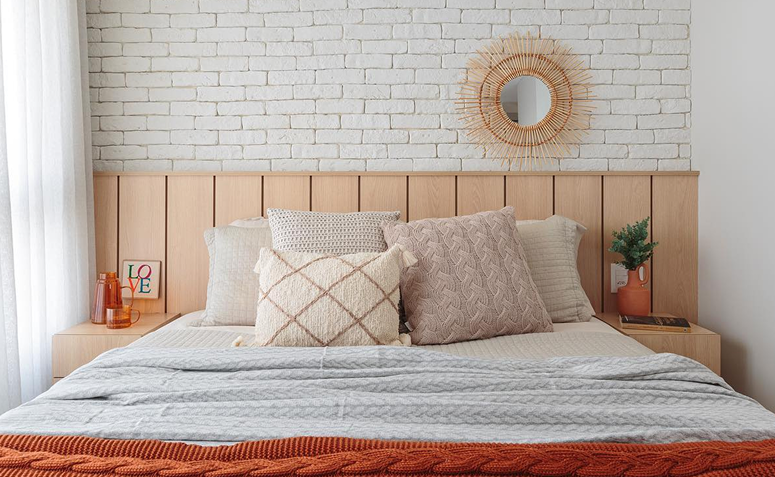 parede atrás da cama com tijolinhos e espelho