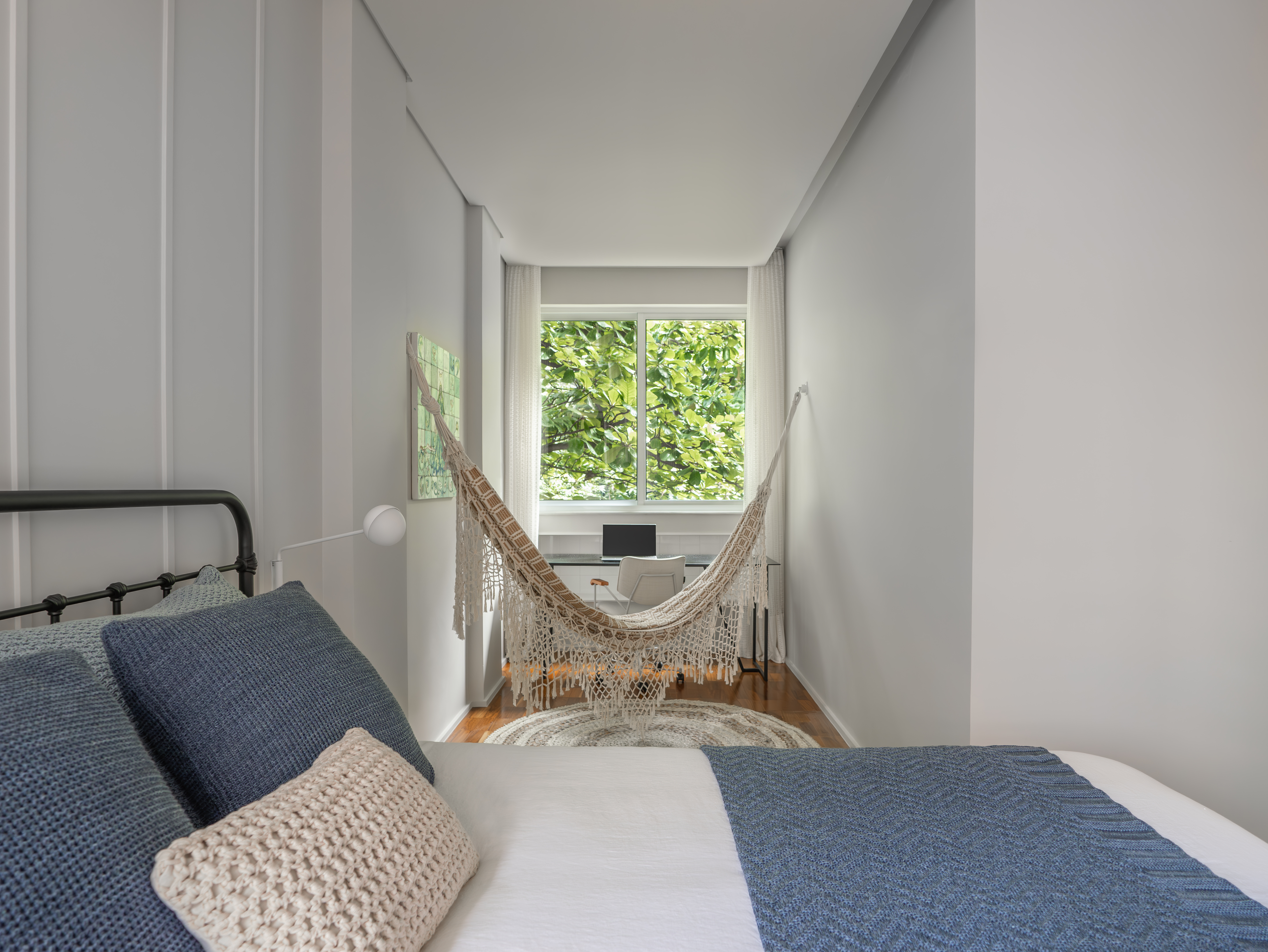 Suíte master com cortina em renda e cantinho de home office com mesa e rede.