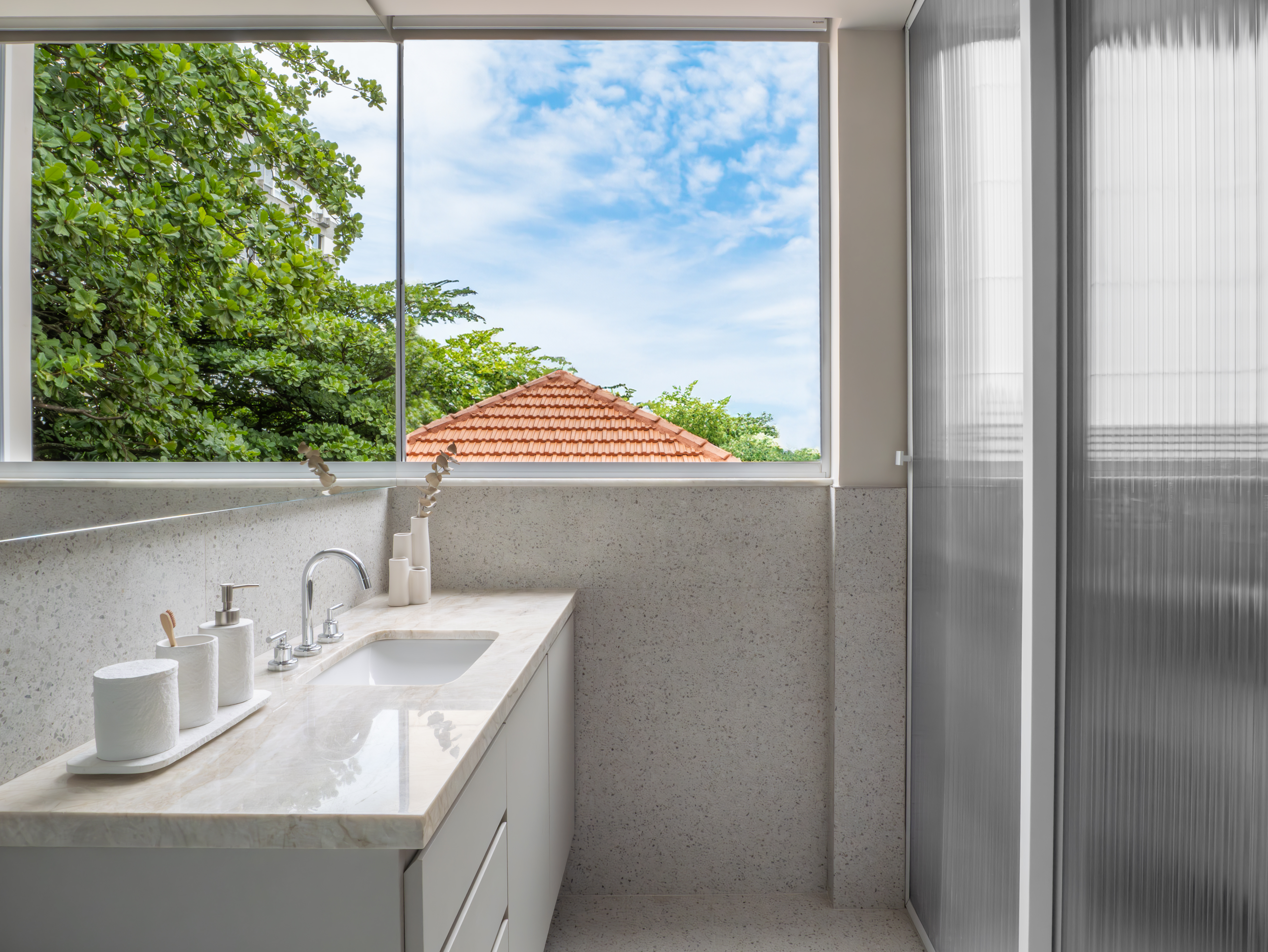 Banheiro com porcelanato que simula granilite, espelho estratégico e iluminação natural, inspirado no design clássico da Bahia