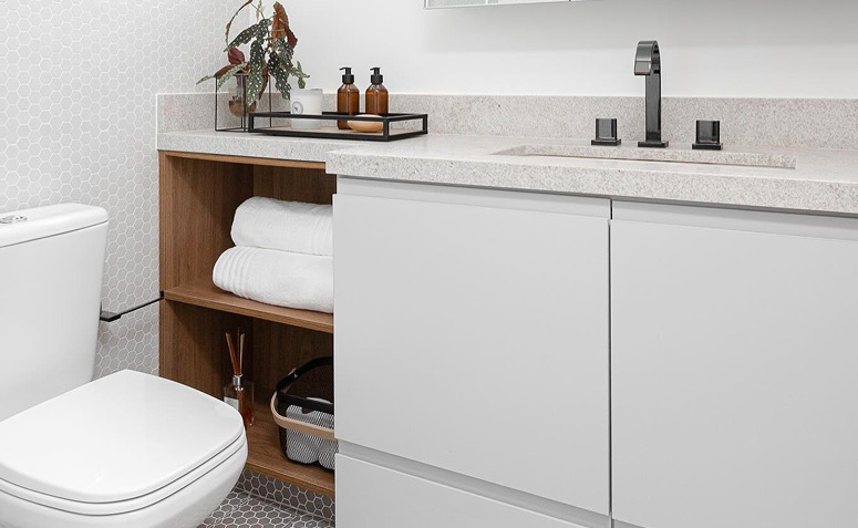 banheiro pequeno com nichos e prateleiras organizadas com produtos de higiene e toalhas.