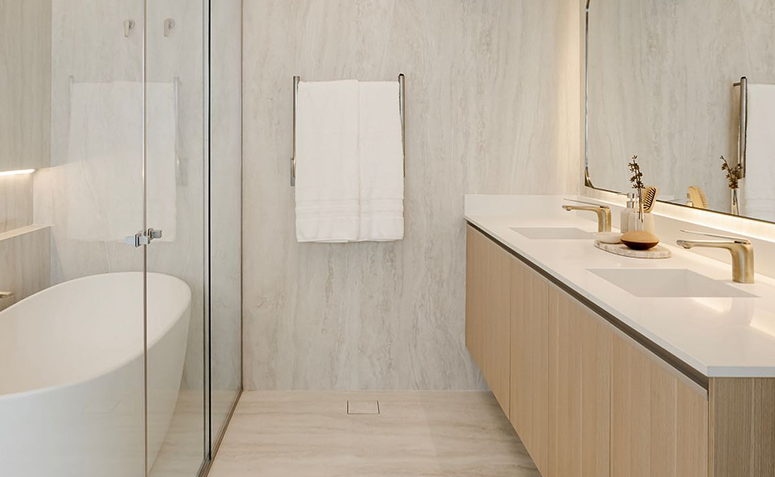 toalhas brancas penduradas em banheiro com tons neutros e bancada de madeira, transmitindo sensação de aconchego