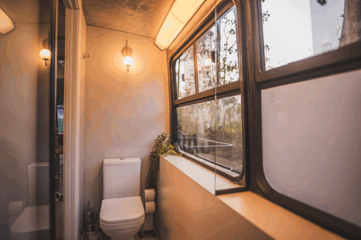 banheiro compacto do ônibus casa com vaso sanitário, janela original e acabamento moderno