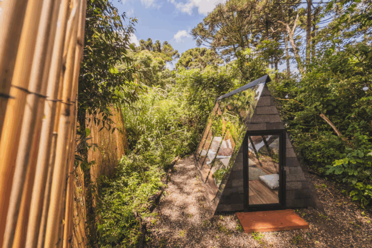 cabana transparente ao ar livre rodeada por árvores e vegetação, em meio à natureza da chácara