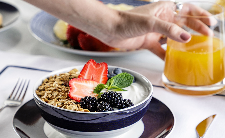 Anfitrião servindo aos convidados à mesa de forma organizada e natural.