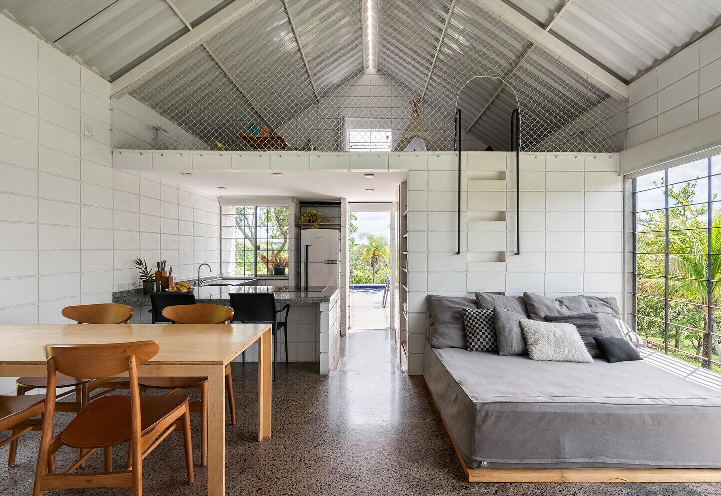 Vista interna da área social da casa, incluindo sala de estar, sala de jantar e cozinha.