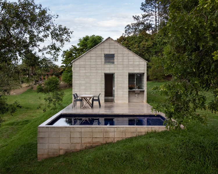 Vista externa da casa mostrando a varanda, piscina e a área verde em volta.