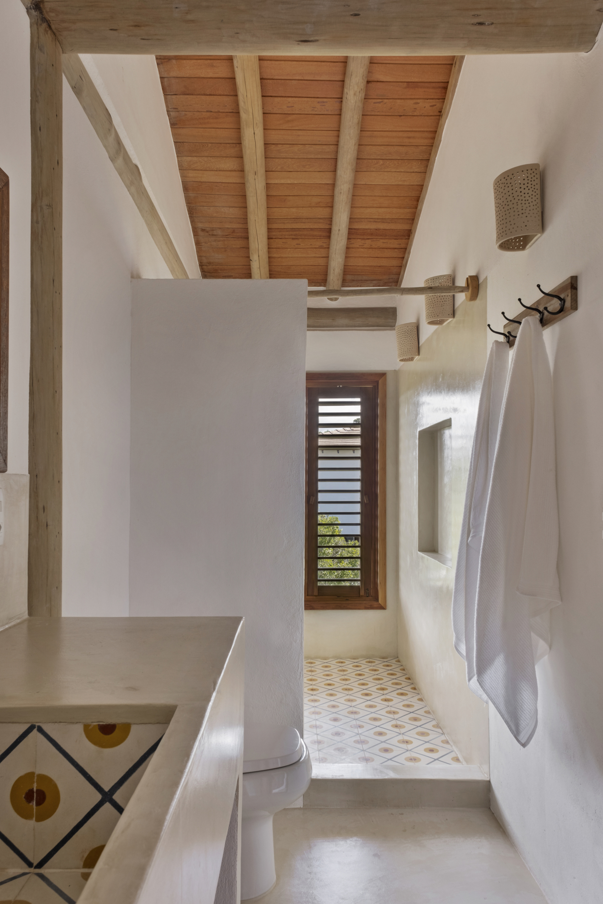 Banheiro de casa de praia em Trancoso com revestimentos claros, ventilação natural e soluções simples para conforto térmico