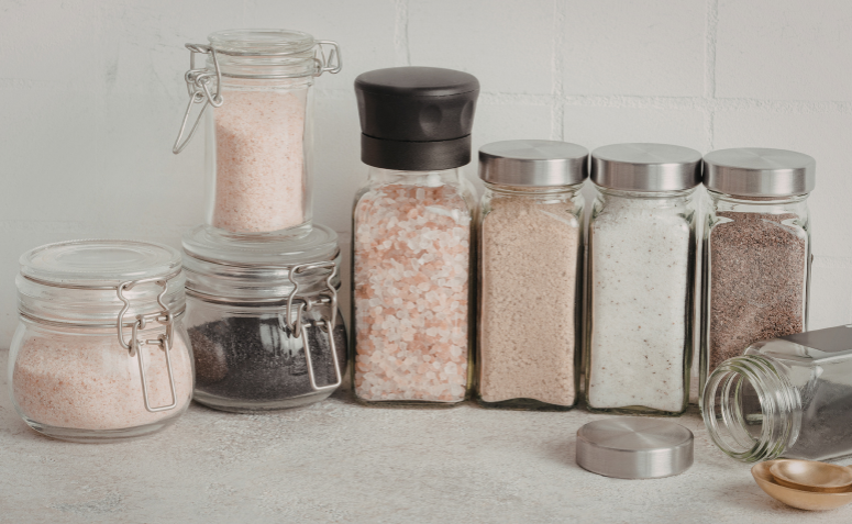 Temperos em frascos de vidro com tampa sobre uma bancada.