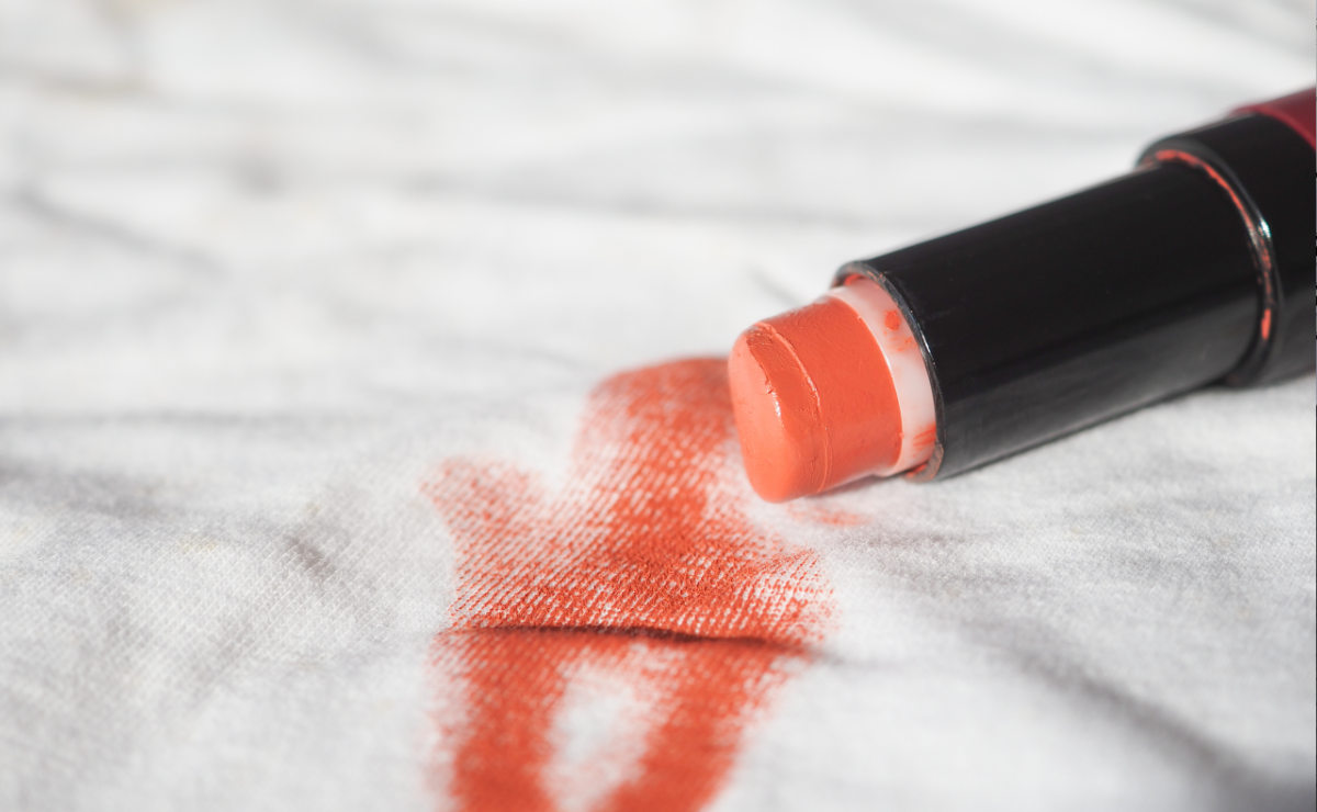 Batom coral aberto mancha tecido branco. A cor intensa contrasta com o pano claro.