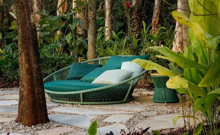 canto reservado no jardim com sofá externo e almofadas cercado por plantas