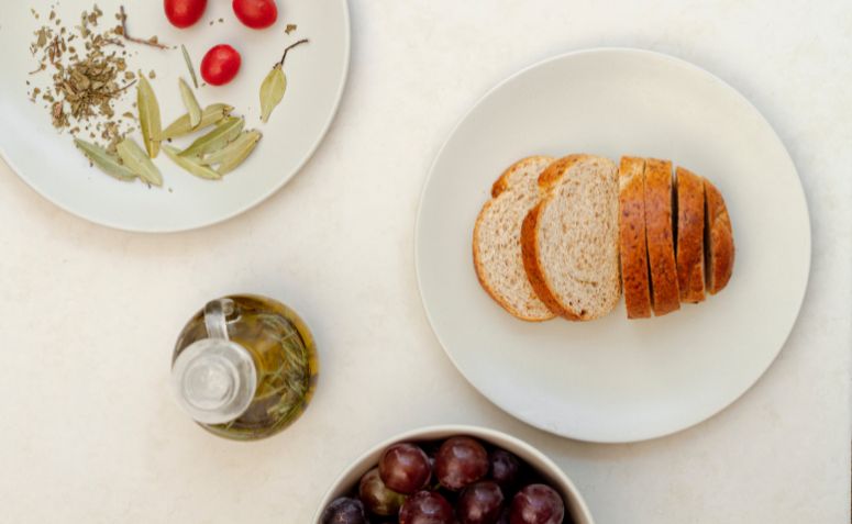 Composição minimalista com pratos brancos: um deles com fatias de pão e outro com tomates e ervas.Composição minimalista com pratos brancos: um deles com fatias de pão e outro com tomates e ervas.