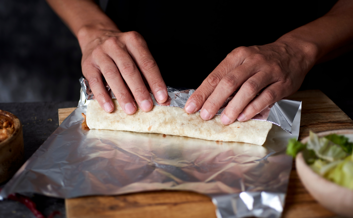 pessoa usando papel alumínio para envolver alimento na cozinha