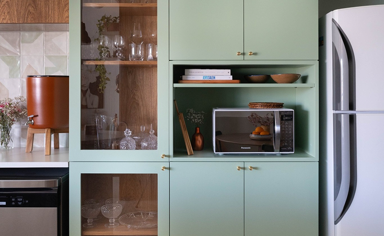 cozinha planejada com micro-ondas instalado em nicho verde integrado à marcenaria.