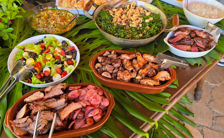 churrasco servido em evento com salada, carnes e acompanhamentos.
