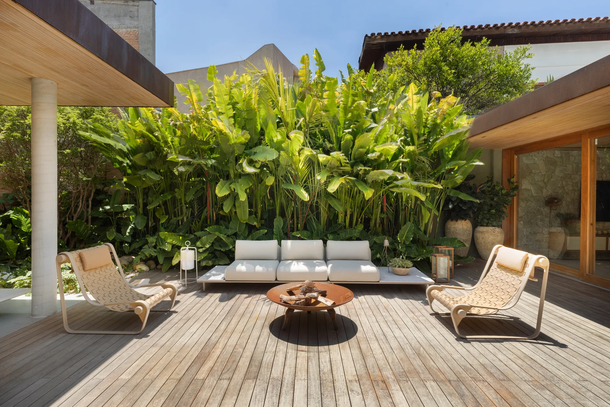 jardim tropical na Casa Moema com lareira externa e móveis baixos.
