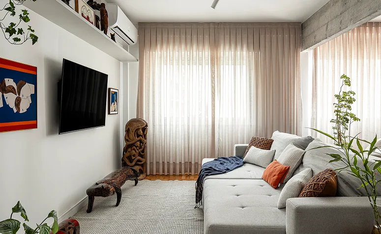 Sala compacta com sofá em frente à TV instalada na parede, representando a distância entre a tela e os principais pontos de uso.