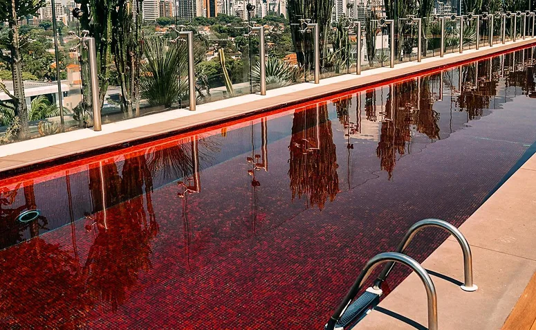 Piscina vermelha em projeto contemporâneo, com água de aparência intensa e efeito cenográfico na área externa.