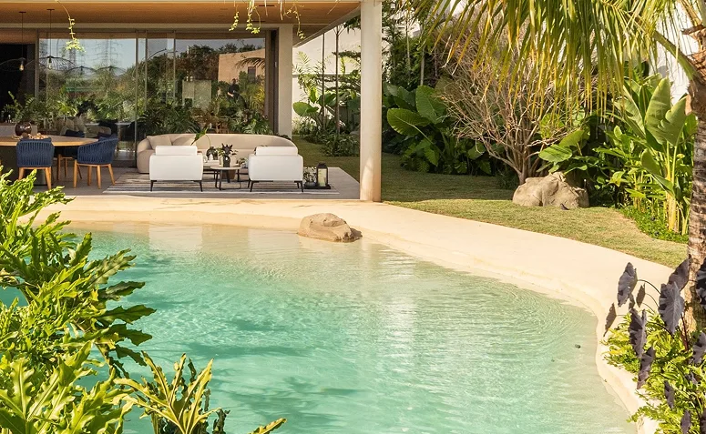 Piscina com revestimento em tom areia, criando água clara e sensação de praia em casa.