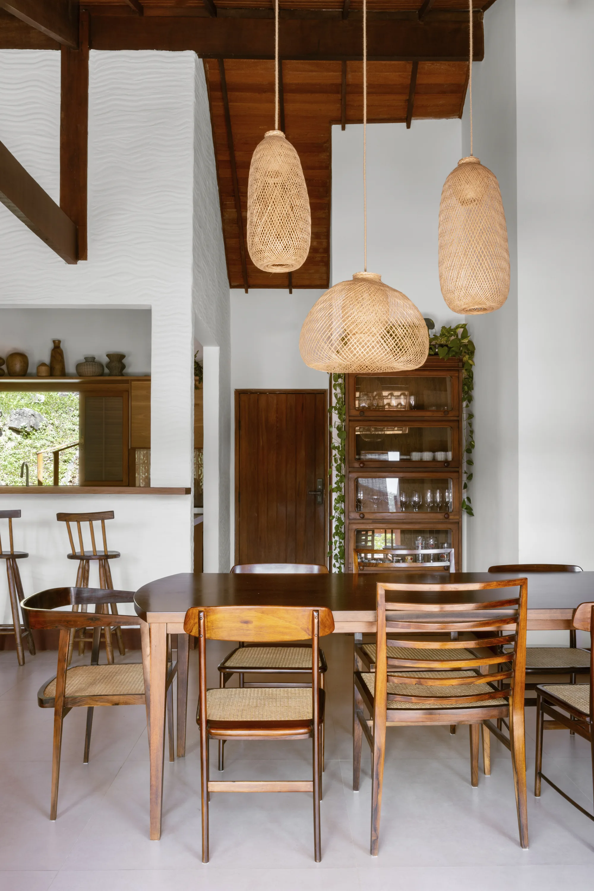 Cristaleira, luminária artesanal e cadeiras de design compõem decoração afetiva em casa reformada.