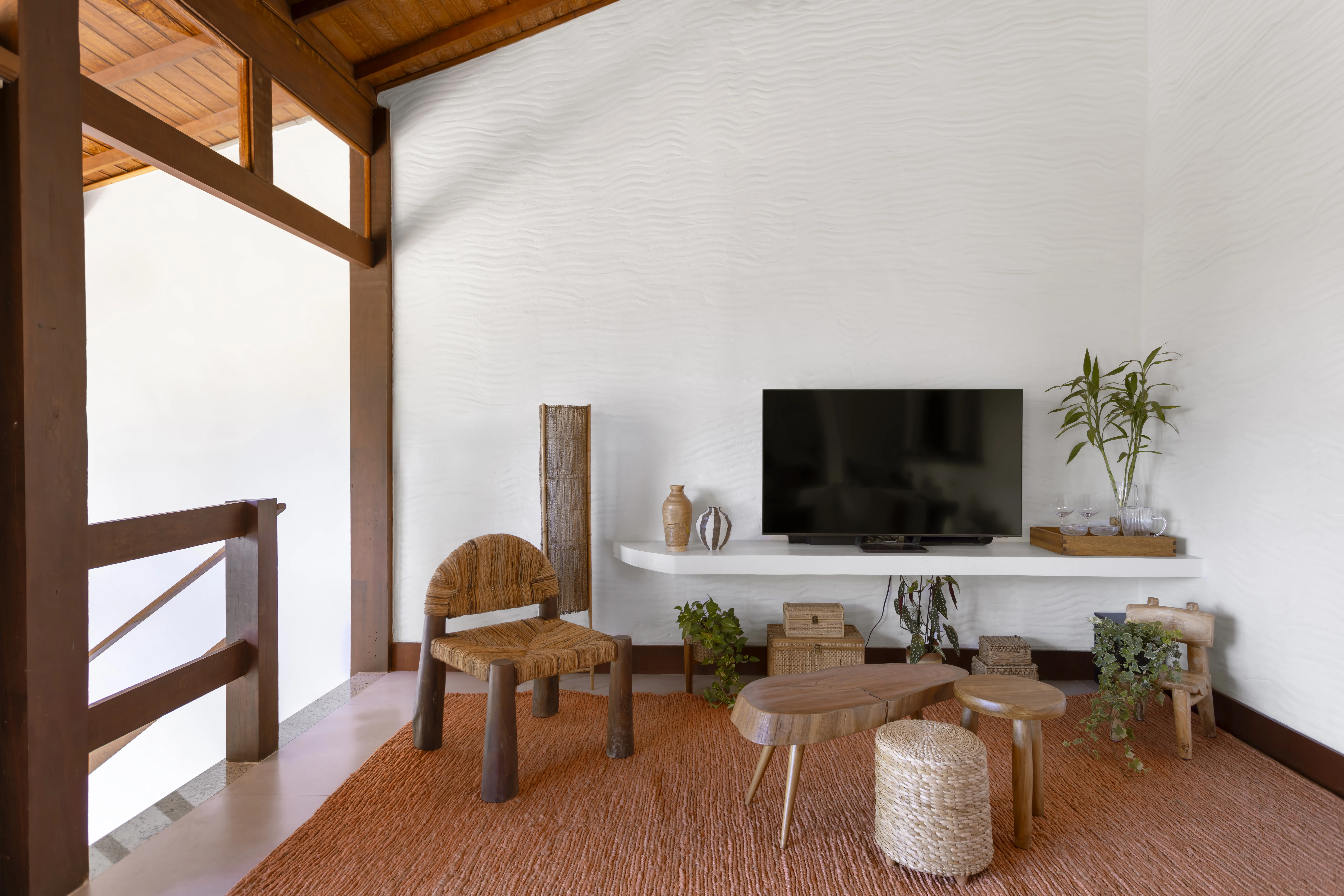 Sala de estar com teto de madeira, parede branca texturizada e decoração natural.