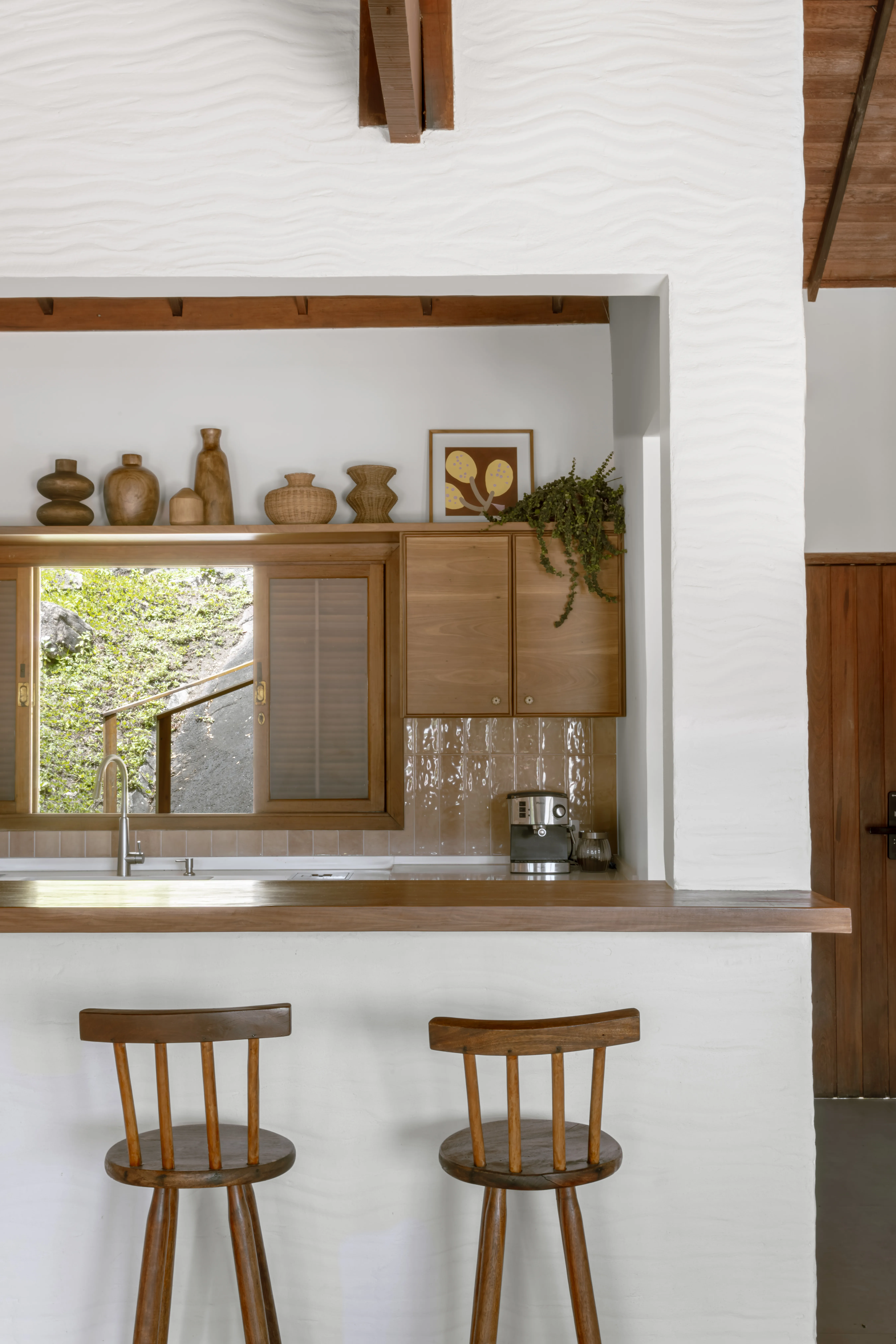 Ambientes sociais integrados em casa de Niterói, com sala, jantar e cozinha conectados visualmente.