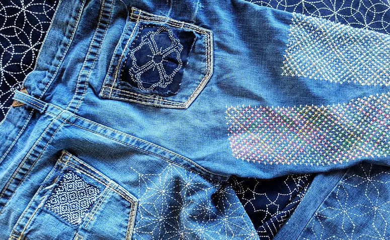 calça jeans com remendos reforçados por bordado sashiko, destacando o reaproveitamento do tecido
