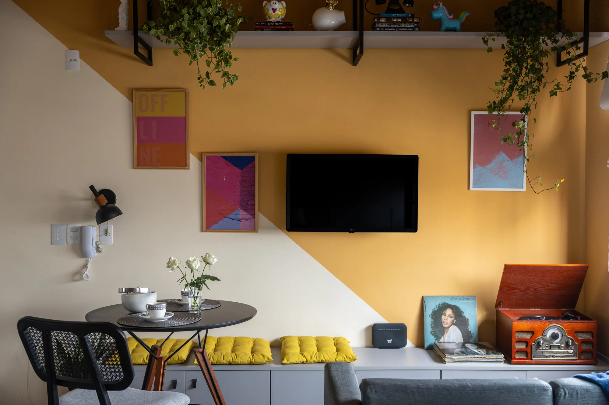 Studio de 25 m² com pintura geométrica em amarelo mostarda nas paredes e no teto, décor colorido e referências retrô.
