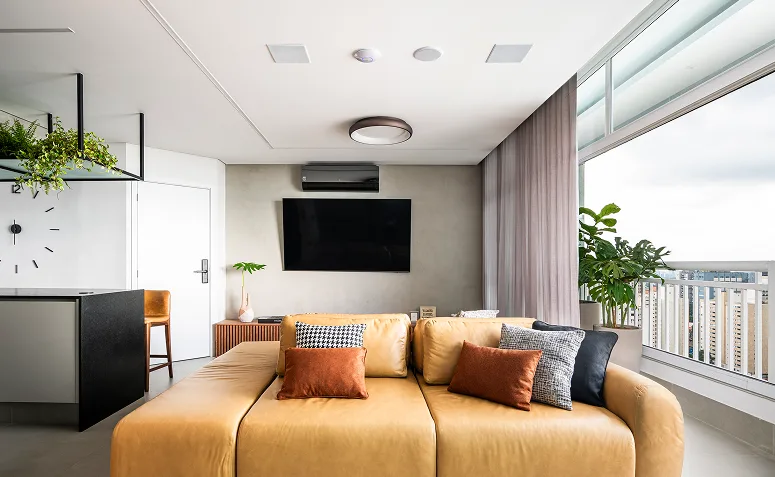 sofá caramelo em sala integrada com parede neutra e decoração contemporânea.