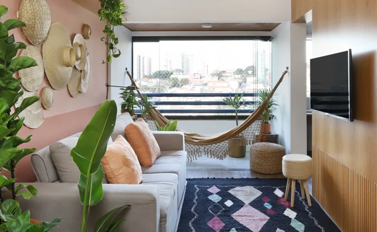 sofá claro com almofadas, tapete e objetos decorativos criando unidade com as cores da sala.