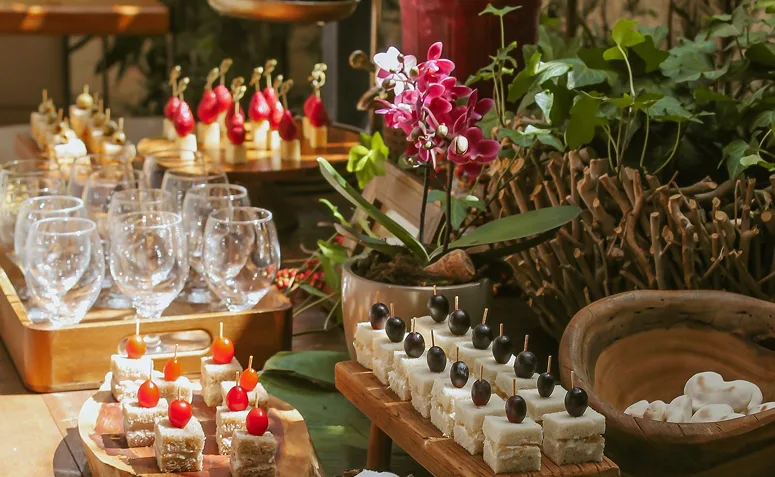 Mesa decorada com petiscos individuais, taças, flores e opções salgadas para um brunch