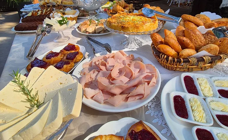 Buffet de brunch com pães, frios, queijos, quiche, geleias e preparos doces e salgados