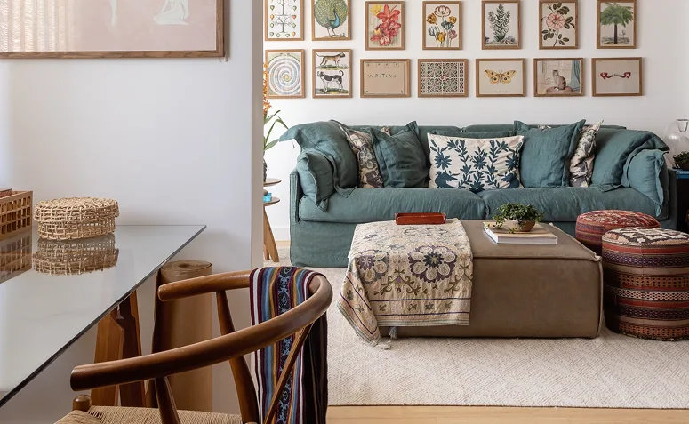 Sala com decoração boho, sofá verde, quadros, tecidos estampados e móveis de diferentes estilos