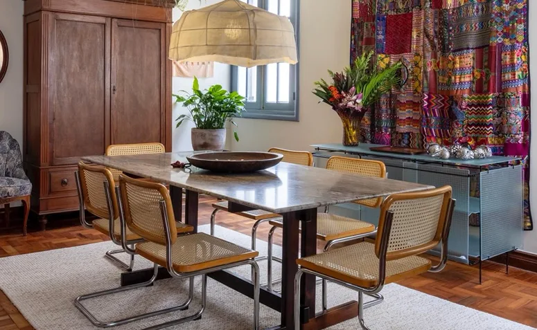 Sala de jantar boho com tapeçaria colorida, móveis de madeira, palhinha e plantas