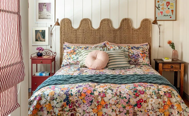 Quarto boho com cabeceira de fibra natural, roupa de cama floral e móveis de madeira