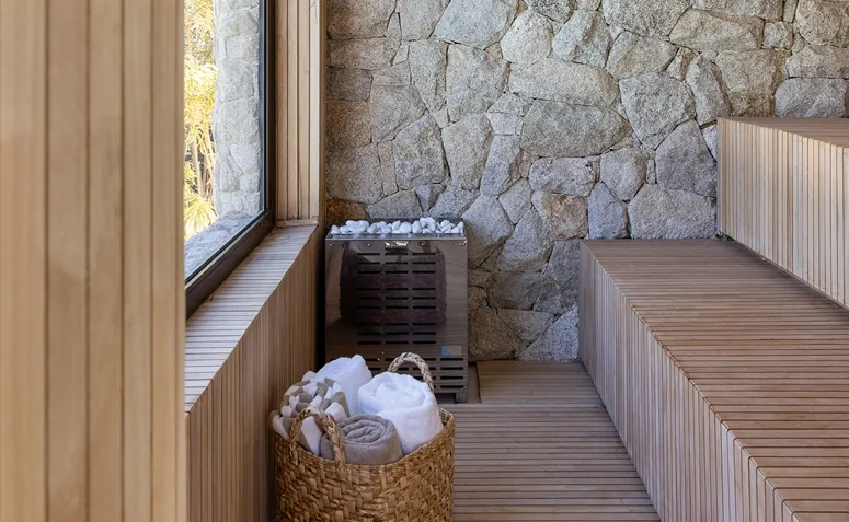 sauna com revestimento de madeira e pedra natural em área interna.