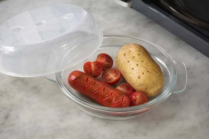 Batata furada, salsicha cortada e tomates ao meio em prato próprio para micro-ondas.