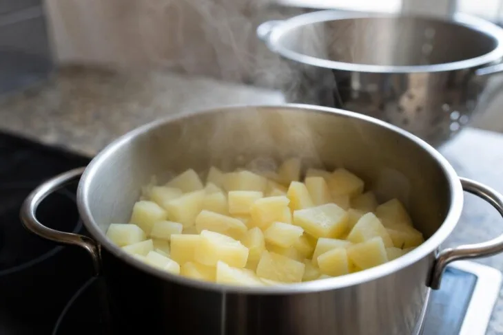 Batatas cozidas soltando vapor em panela sem água após serem escorridas.