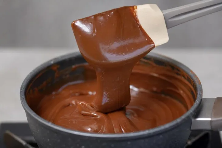 Brigadeiro mole caindo da espátula em faixa grossa e brilhante.
